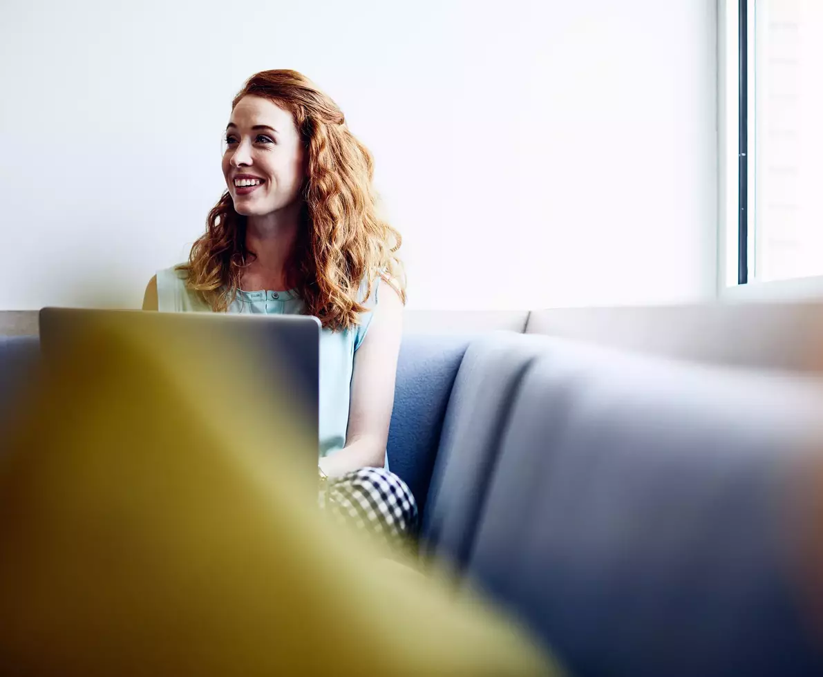 Smiling female with laptop on couch at an office