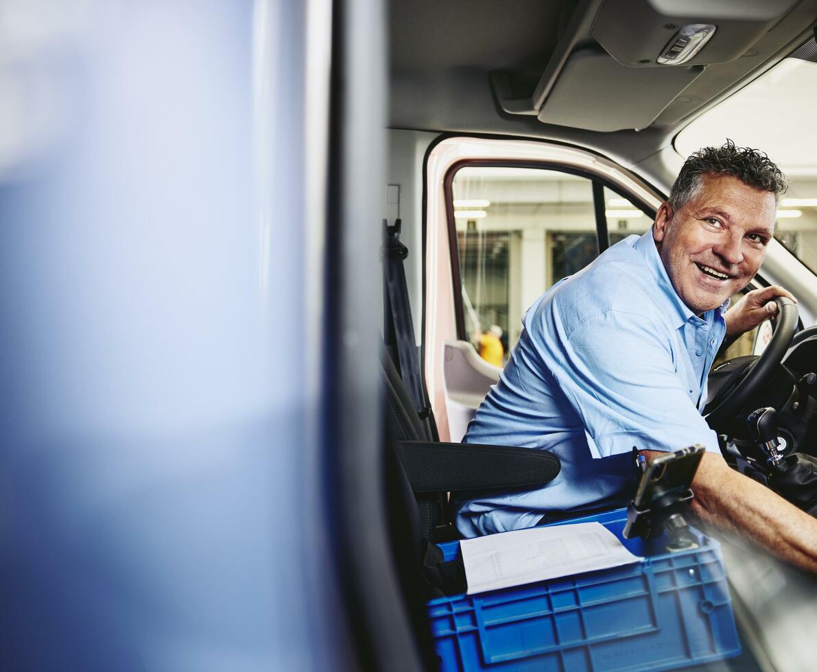 Smiling man sitting in driver's seat of a logistics truck