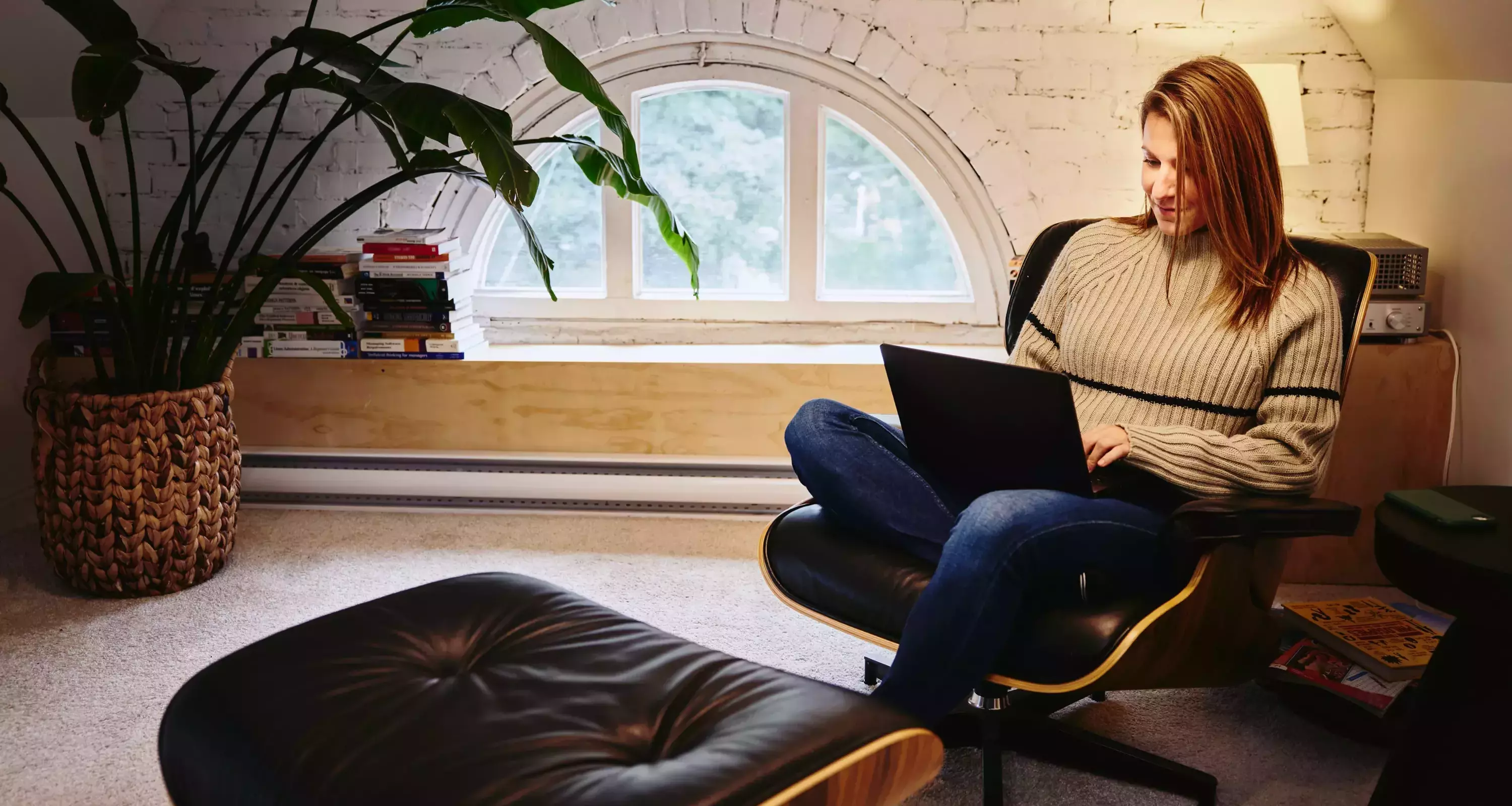 Female sitting in an armchair in a loft working on a laptop