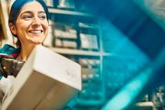 Smiling woman looking away while scanning a package in a warehouse