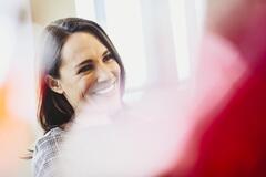 Woman in an office smiling. Primary color: red.