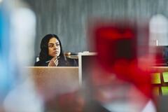 Woman watching over her desk. India. Primary color: red.
